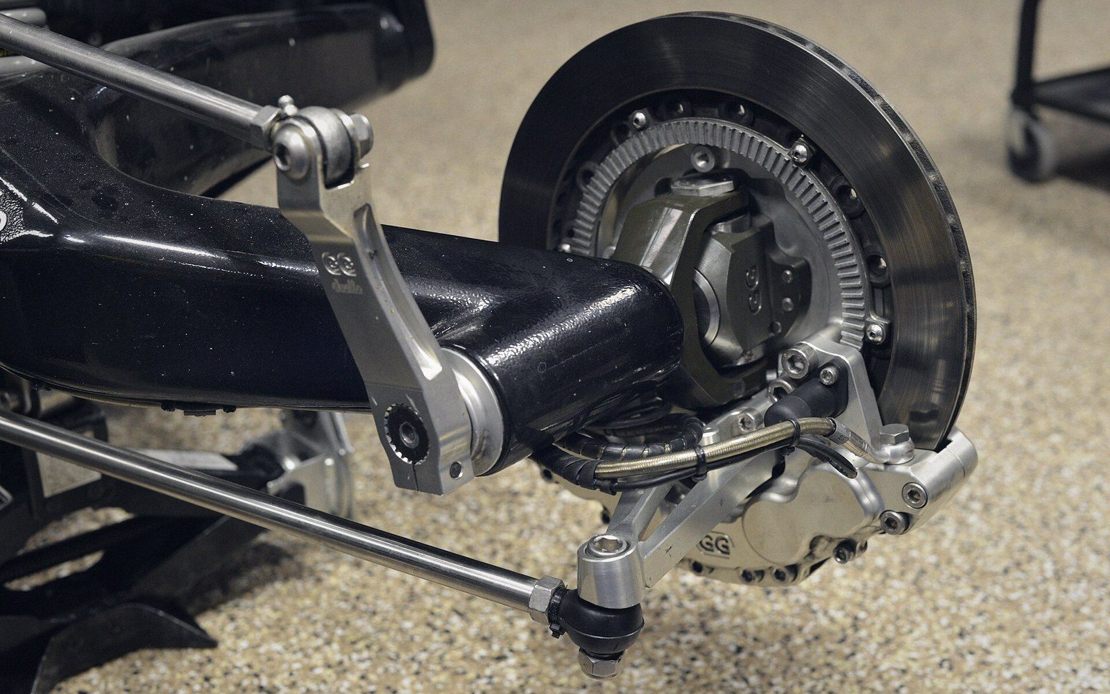 Close-up of a motorcycle hub-centre steering system with brake disc and linkage arms exposed
