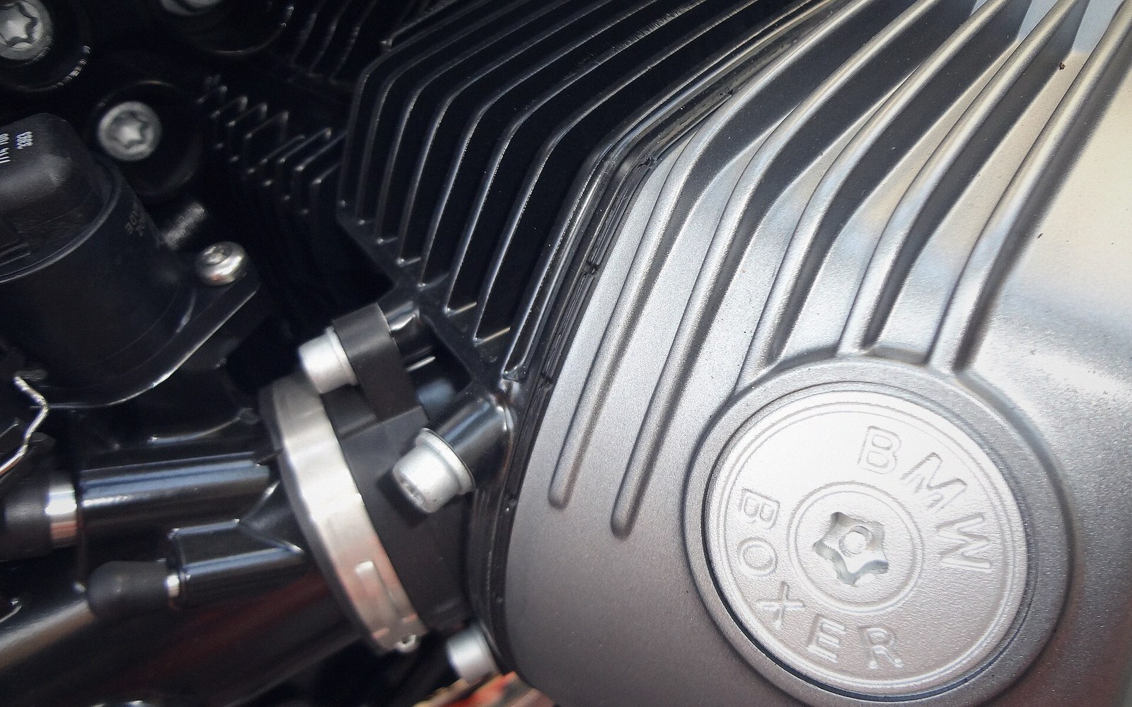 Close-up of a BMW Boxer motorcycle engine's finned cylinder head and cover badge